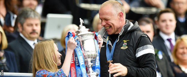 John Hughes is handed the Scottish Cup by his young daughter on the Hampden podium.